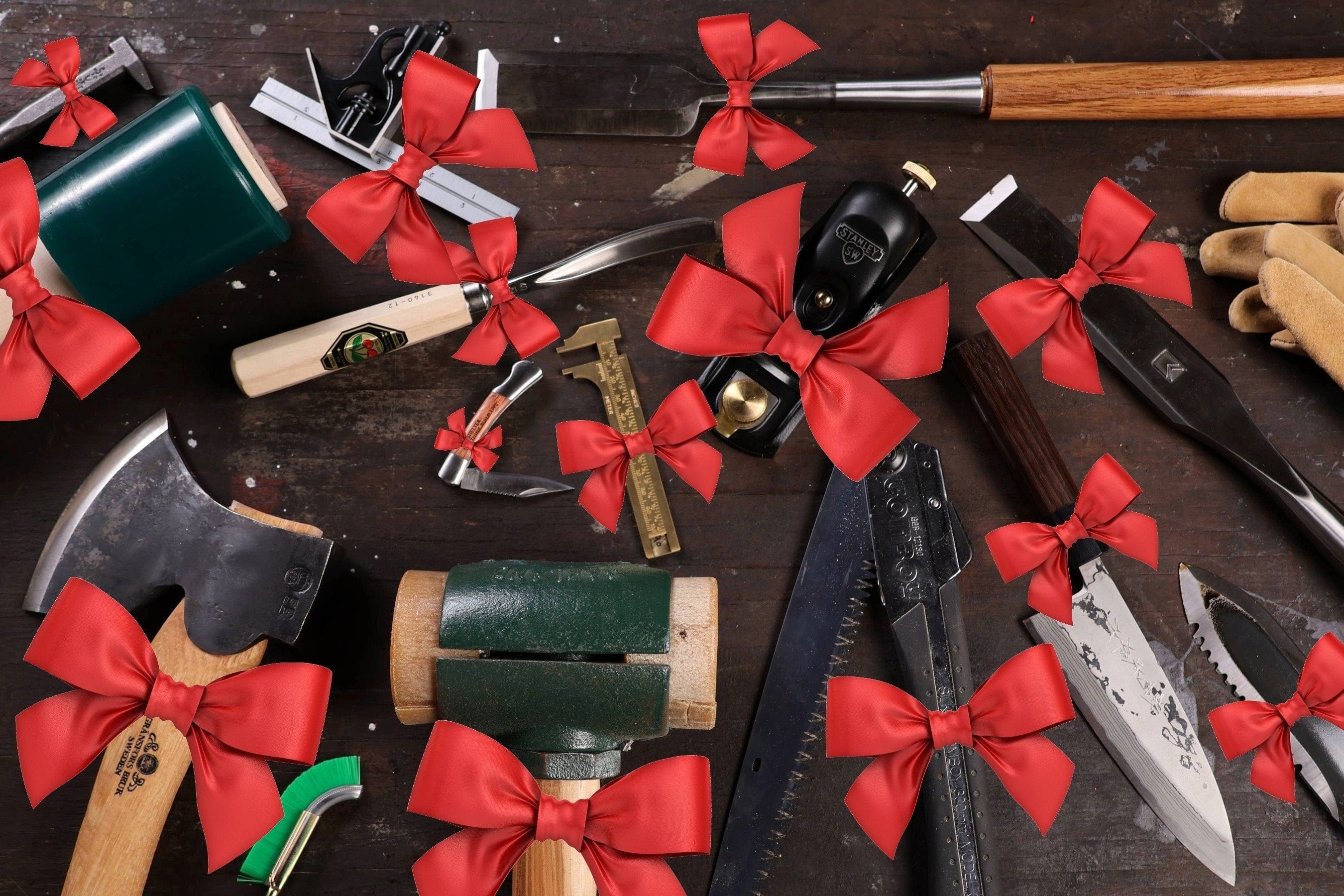 A variety of woodworking tools, including an axe, mallet, chisel, and saw, are spread out on a wooden surface. Each tool is decorated with a large red bow.