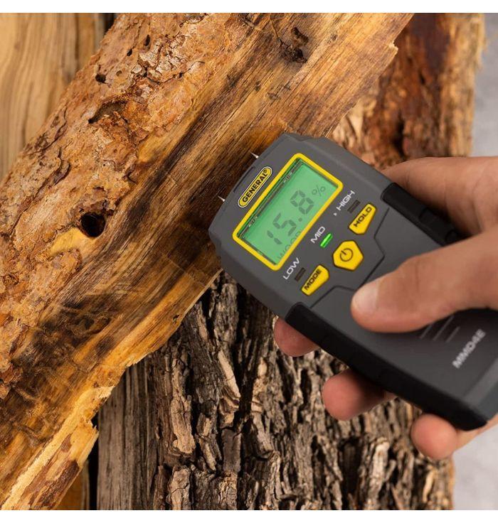 A hand uses the General Tool Company Pin-Type LCD Moisture Meter on rough wood, displaying a 15.8% reading—key for mold prevention and maintaining material quality.
