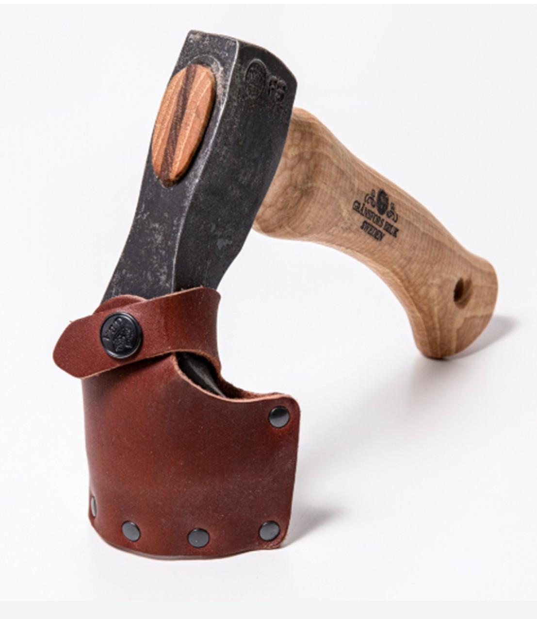 A Gransfors Bruk Small Gutter Adze Radius 25, Second Grade, featuring a compact wooden handle and resembling a small axe ideal for log building or hollowing timber, is displayed on a white background. The blade is protected by a leather sheath secured with brass rivets and a snap button.