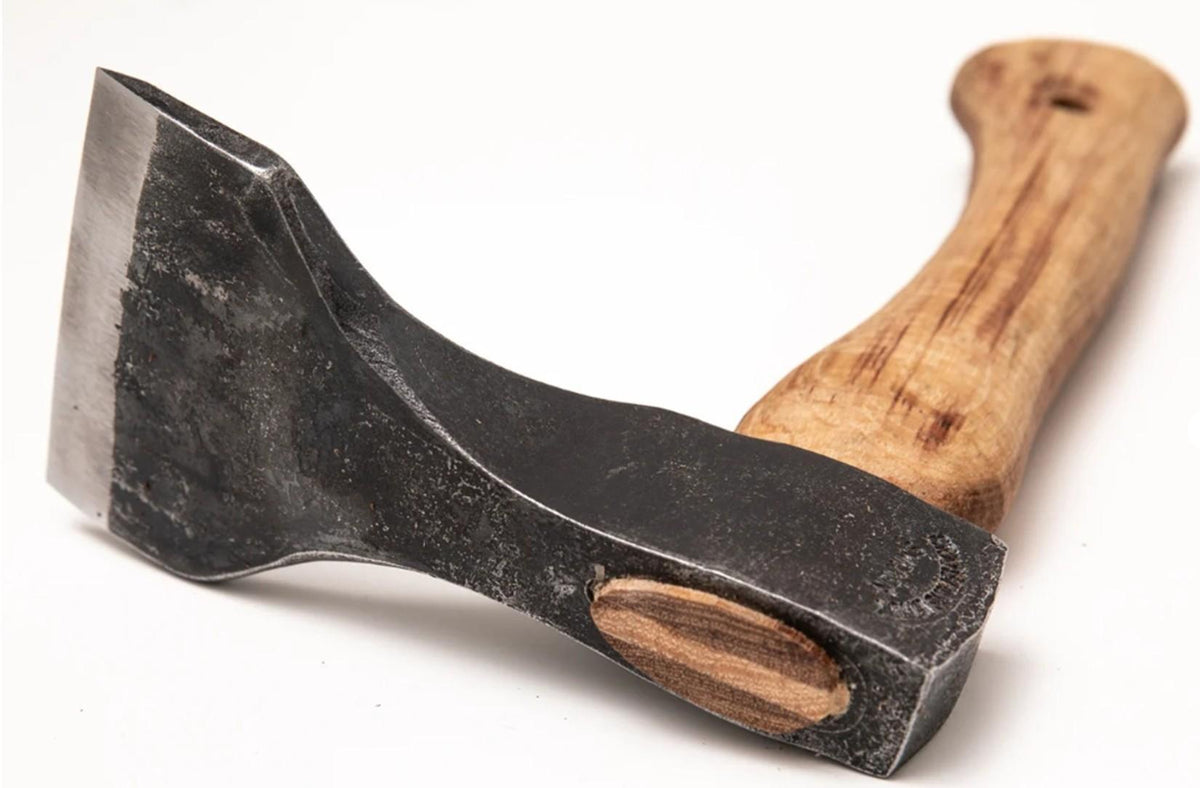 A close-up photo of a Gransfors Small Straight Adze 80 mm from Gransfors Bruks, featuring a black metal head and wooden handle, evocative of traditional craftsmanship, resting on a white surface.