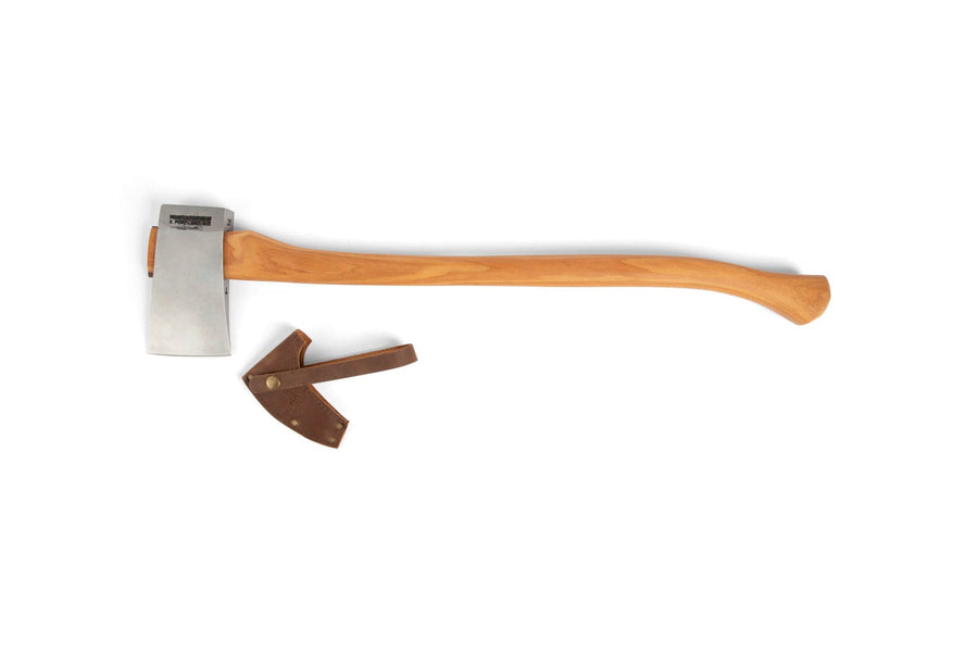The BNC Brant & Cochran Acadian Half Wedge Axe, featuring a durable hickory handle and metal head, lies horizontally on a white background with its brown leather sheath placed nearby.