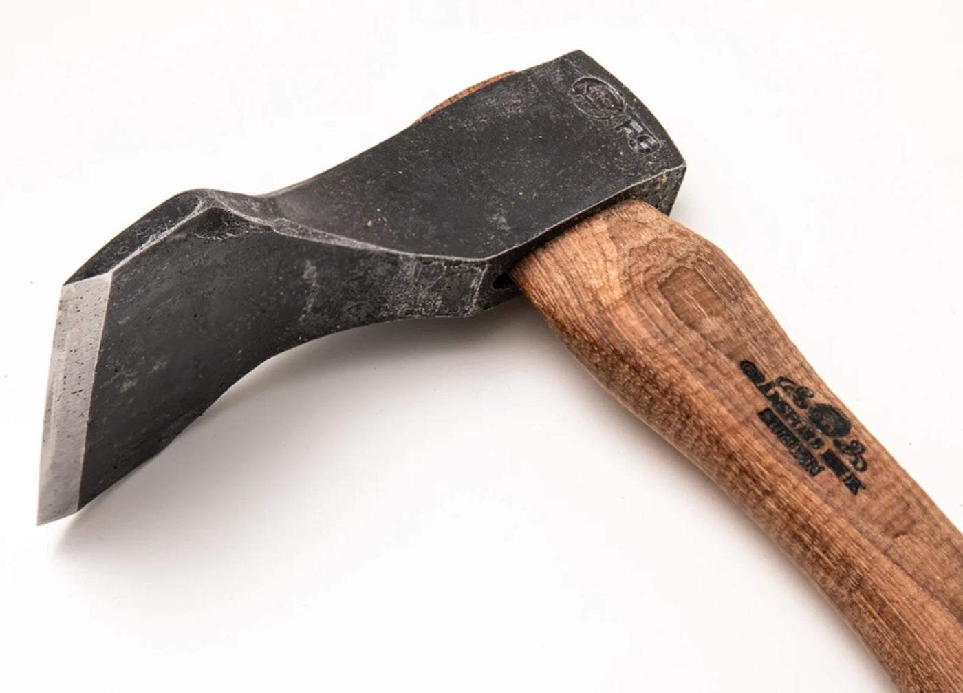 A close-up of the Gransfors Small Straight Adze 80 mm by Gransfors Bruks, featuring a curved wooden handle with a stamped logo and a compact, black-forged metal head, photographed on a plain white background—a specialized tool ideal for log building or intricate detail work.