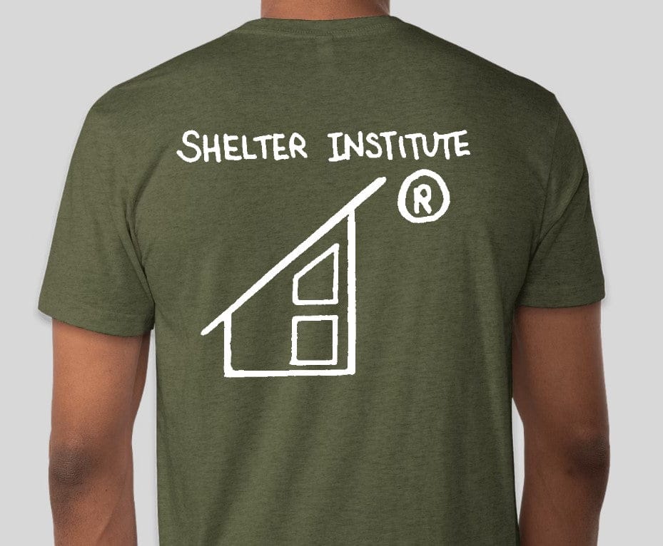 Back view of someone in a green Custom Ink 50th Anniversary Adult T-Shirt featuring "Shelter Institute" and a house illustration, celebrating 50 years of building knowledge.
