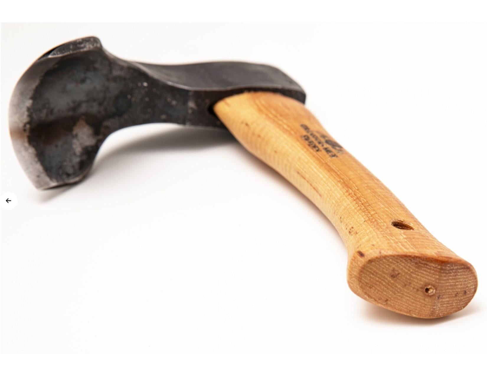 A close-up photo of the Gränsfors Bruk Small Gutter Adze Radius 40 Second Grade, featuring a worn metal head and a wooden handle, placed on a white background, evokes the traditional tools used in log building and hollowing timber.