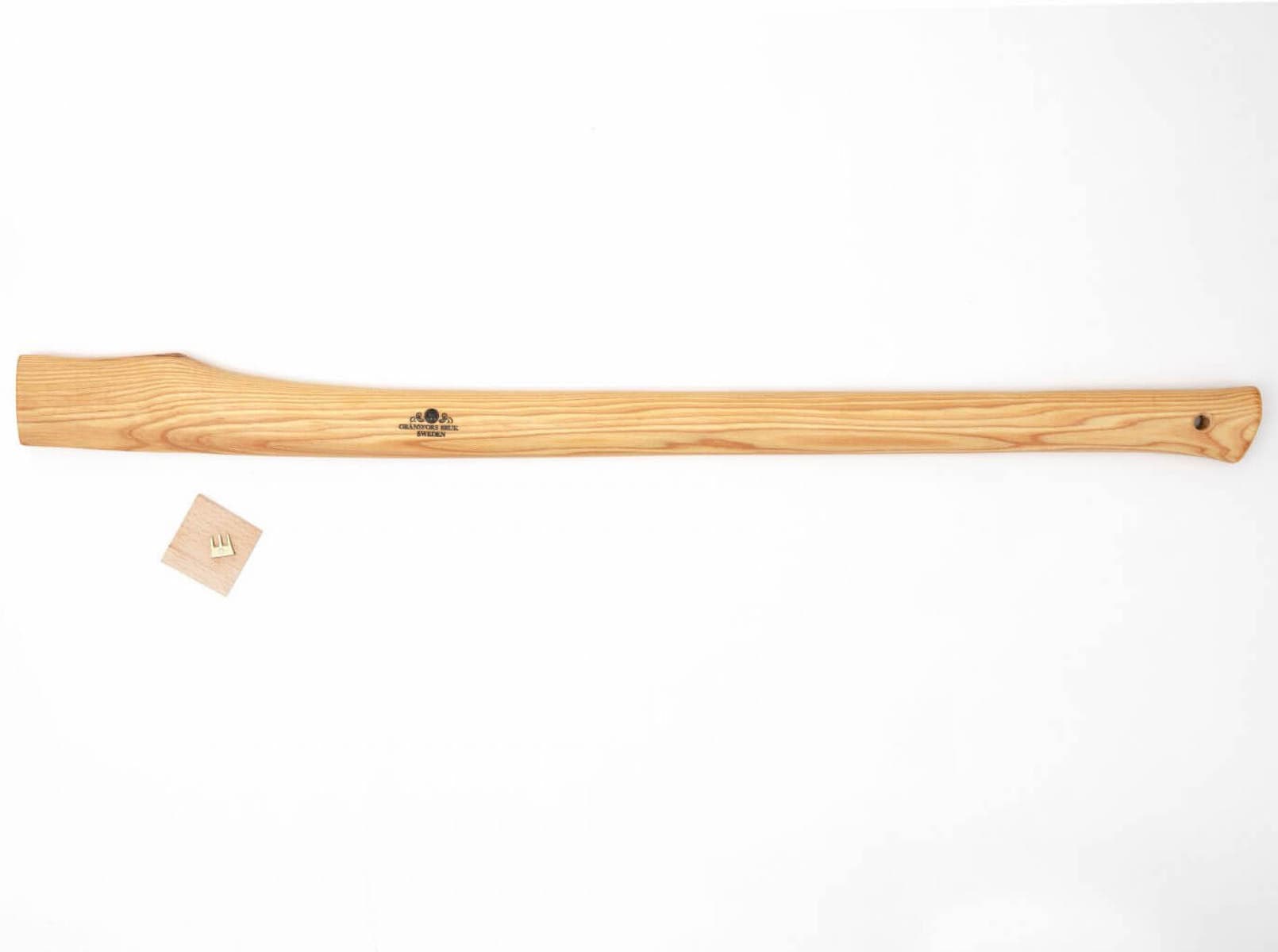 The GRF Gransfors Bruk American Felling Axe 35-in features a long, light wood handle placed horizontally on a white background, with a small square wooden wedge nearby, ideal for traditional forestry work.