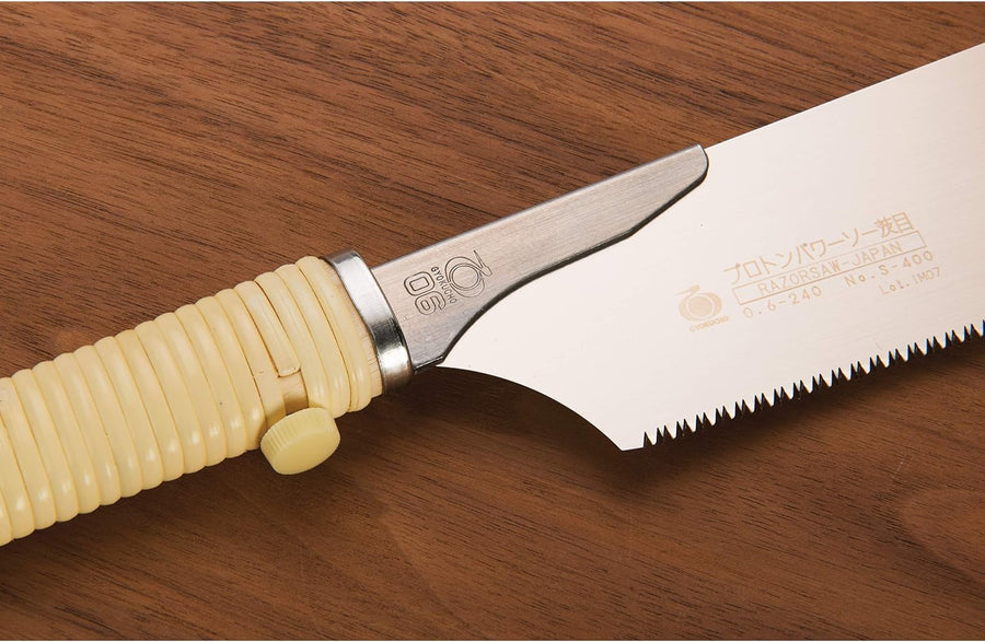 A close-up of the BBT Gyokucho Crosscut Razorsaw No. S-400, featuring a cream ribbed handle and 240mm toothed blade with engraved Japanese text and product details, resting on wood—ideal for woodworking tasks.