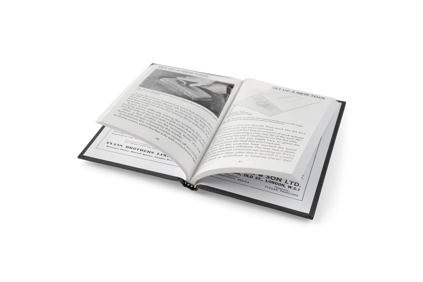 An open copy of Sharpen This by LAP displays black and white pages with text, diagrams, and a photo on sharpening woodworking tools, lying on a white surface.