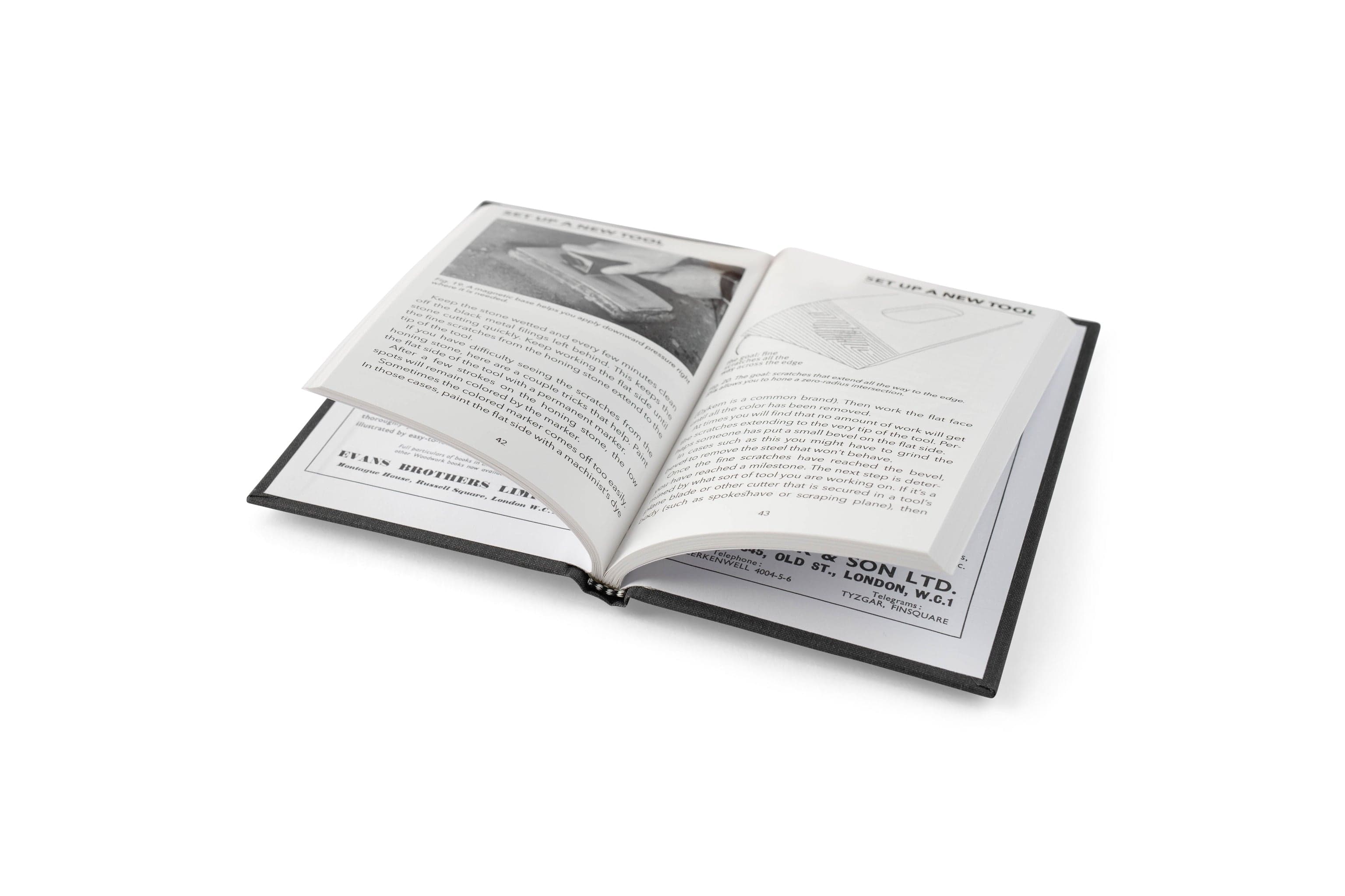 An open copy of Sharpen This by LAP displays black and white pages with text, diagrams, and a photo on sharpening woodworking tools, lying on a white surface.