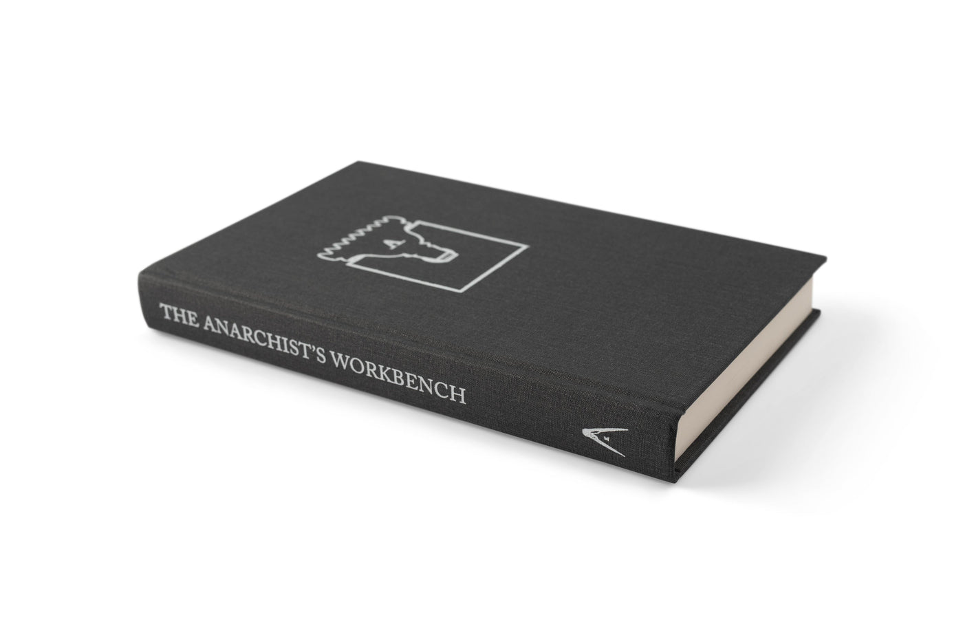 A hardcover copy of LAPs The Anarchists Workbench rests closed on a white surface, its black cover displaying a white line drawing of a workbench that showcases traditional joinery and minimalist woodworking design.