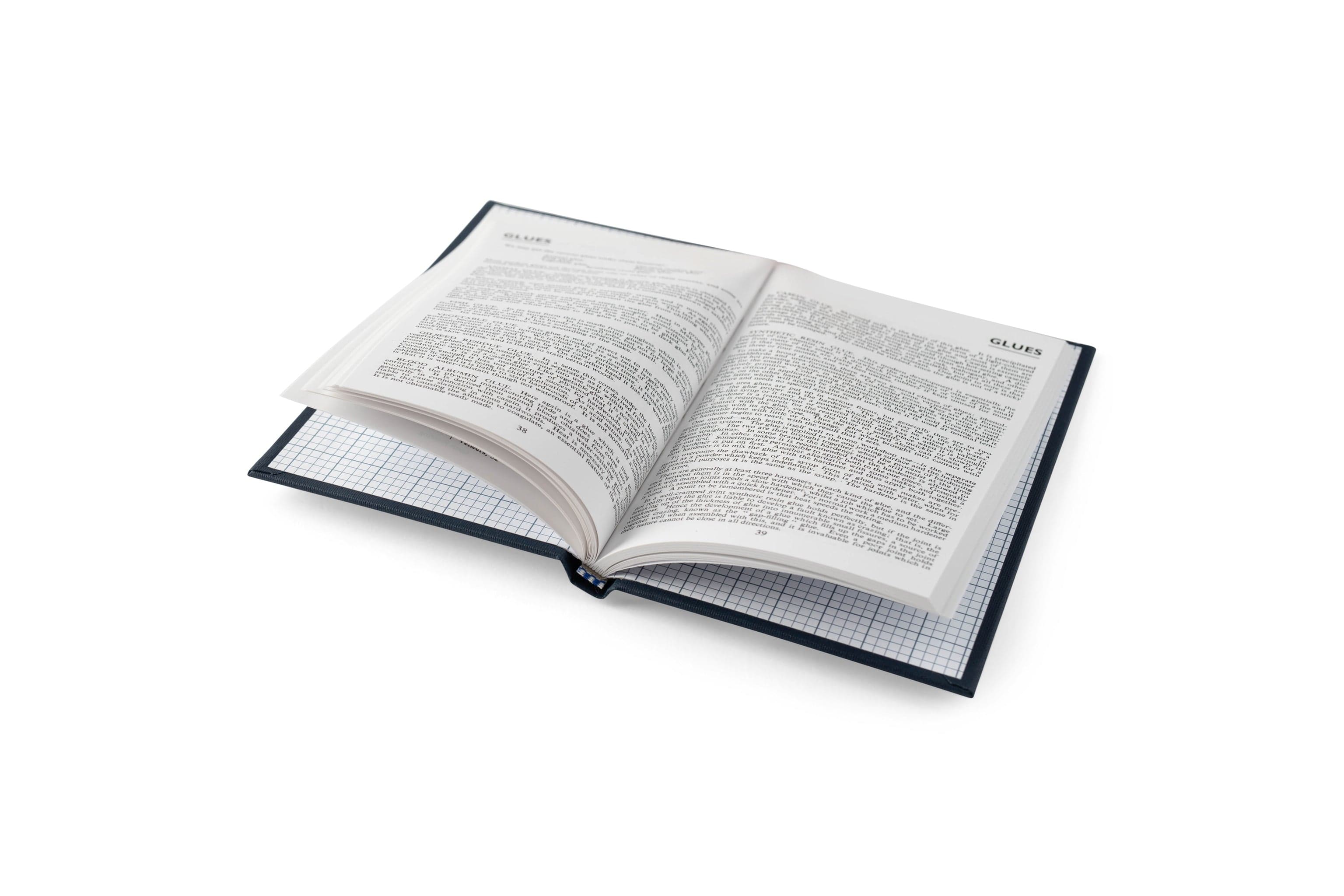 An open LAP The Woodworker’s Pocket Book hardcover rests on a graph paper notebook against a white background, its printed text visible.