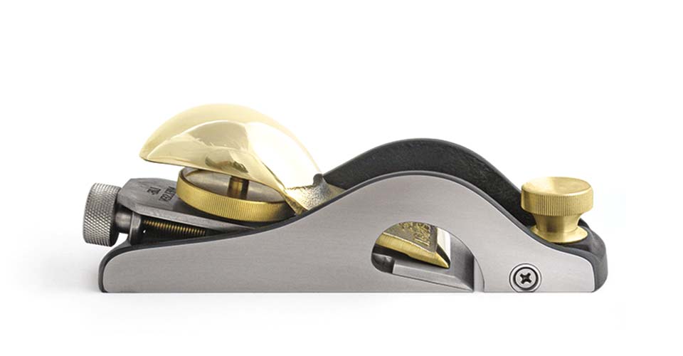 The Lie-Nielsen 60-1/2 Rabbet Block Plane with Nicker is a metallic woodworking tool with brass components and a shiny silver finish, ideal for therapeutic woodworking.