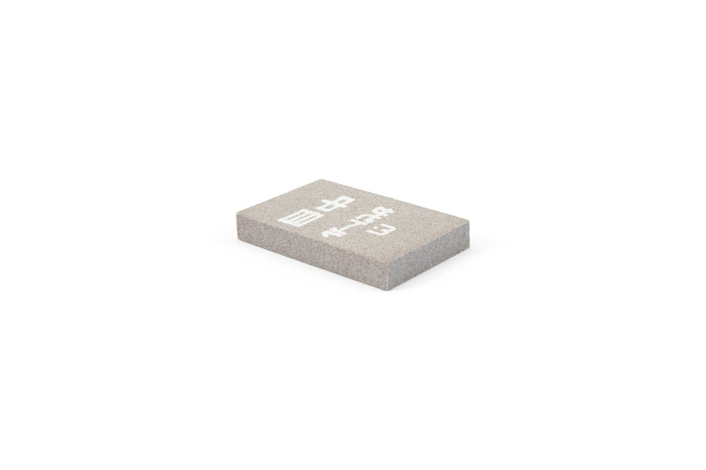 A single rectangular gray mahjong tile with white Chinese characters, its smooth finish similar to the effect of the MARU Japanese Rust Eraser used for cleaning steel tools, is placed on a plain white background.