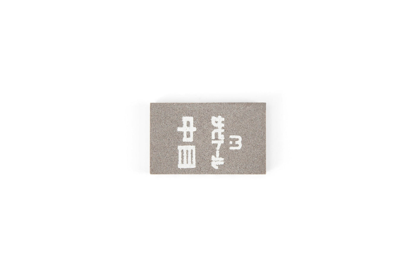 The MARU Japanese Rust Eraser is a small, rectangular gray eraser with white Japanese characters, perfect for removing rust from steel tools. Displayed on a plain white background.