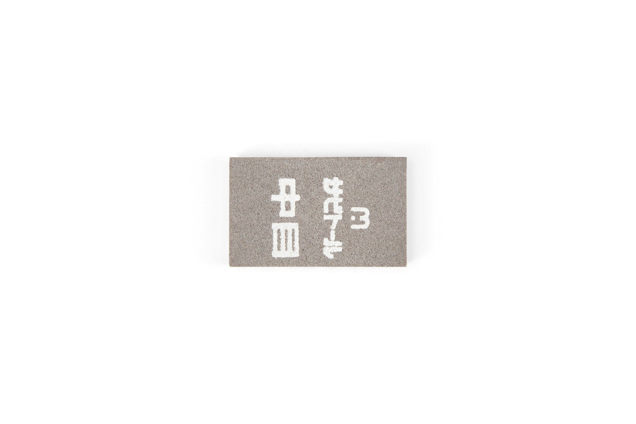 The MARU Japanese Rust Eraser is a small, rectangular gray eraser with white Japanese characters, perfect for removing rust from steel tools. Displayed on a plain white background.