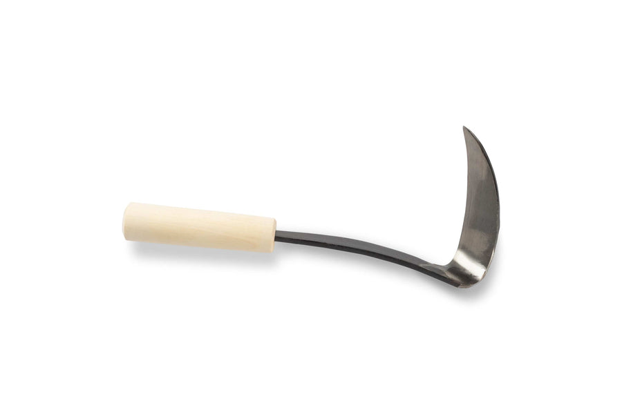 The Japanese Scythe Weeder by MARU, featuring a wooden handle and a curved high-carbon steel blade, lies against a white background.