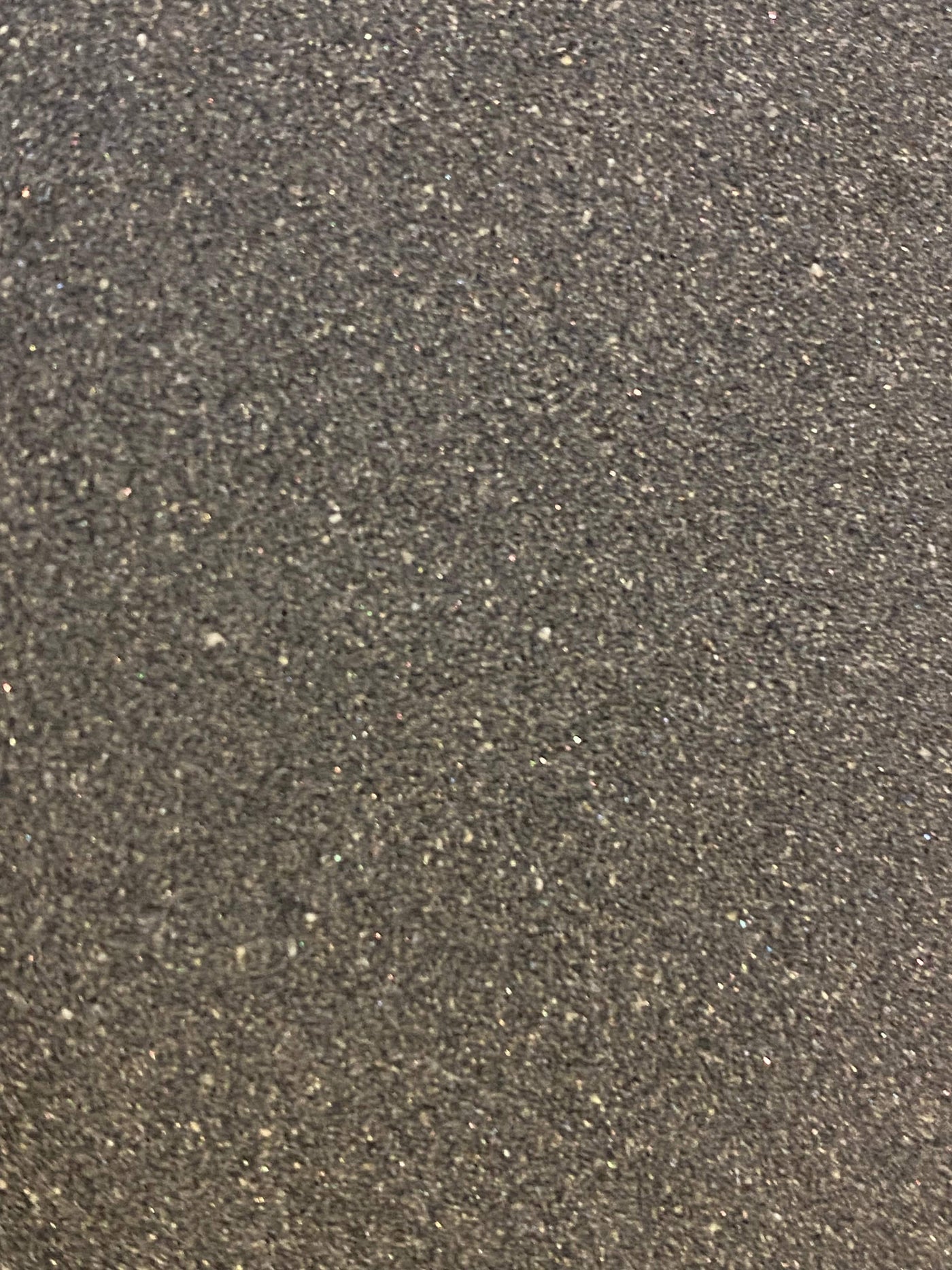 A close-up of a textured surface covered in gray and black speckles, reminiscent of the fine abrasion seen on the MARU 180 Grit Japanese Water Stone.