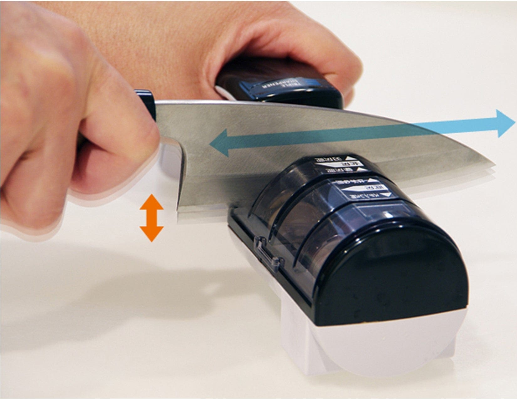 A person precisely sharpens a kitchen knife using the MARU Suehiro Triple Knife Sharpener, guiding the blade smoothly across it. Arrows indicate motion direction.