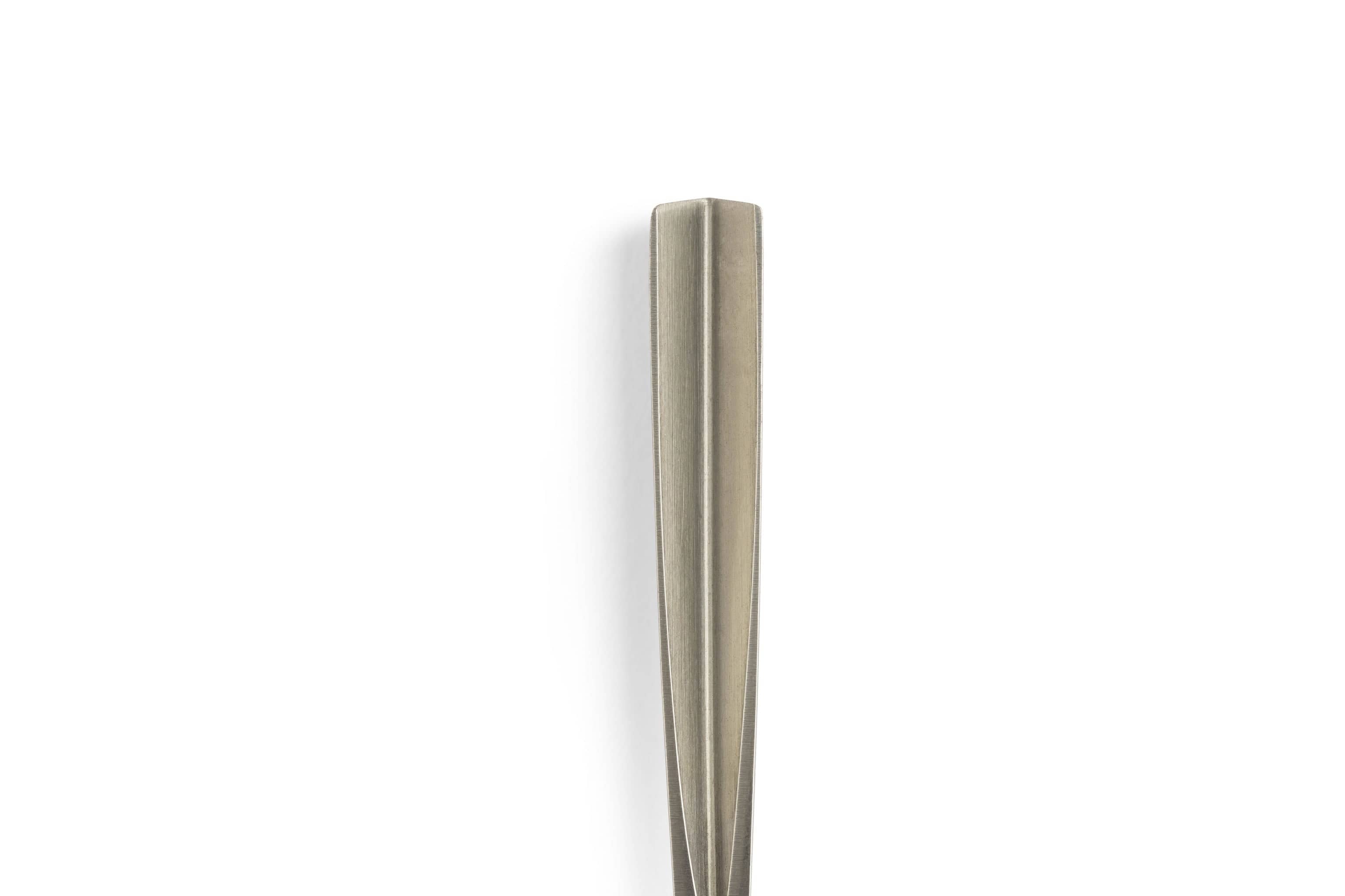 A close-up of the top portion of a sleek metal fork handle, vertically positioned against a white background, showcases design elements inspired by the professional craftsmanship of the MHG Wood Carving Knife and Gouge Set by MHG.