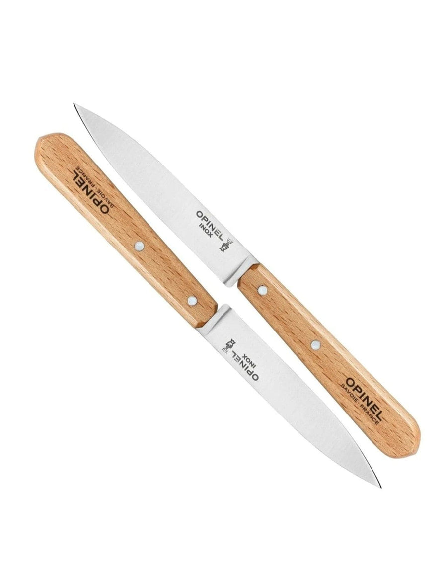 Two Opinel Paring Knives from the Opinel Paring Knives Set of Two, featuring beech wood handles and stainless steel blades with visible Opinel branding, are arranged in a crisscross pattern on a white background.