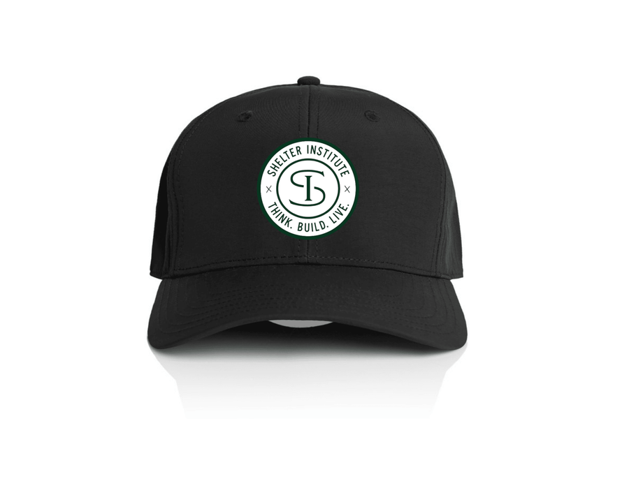The Shelter Institute Nylon Dad Cap by Riptide Print Company features a circular white logo reading Shelter Institute and Think. Build. Live. around a stylized "SI" on the front, inspired by timber frame craftsmanship, shown against a white background.