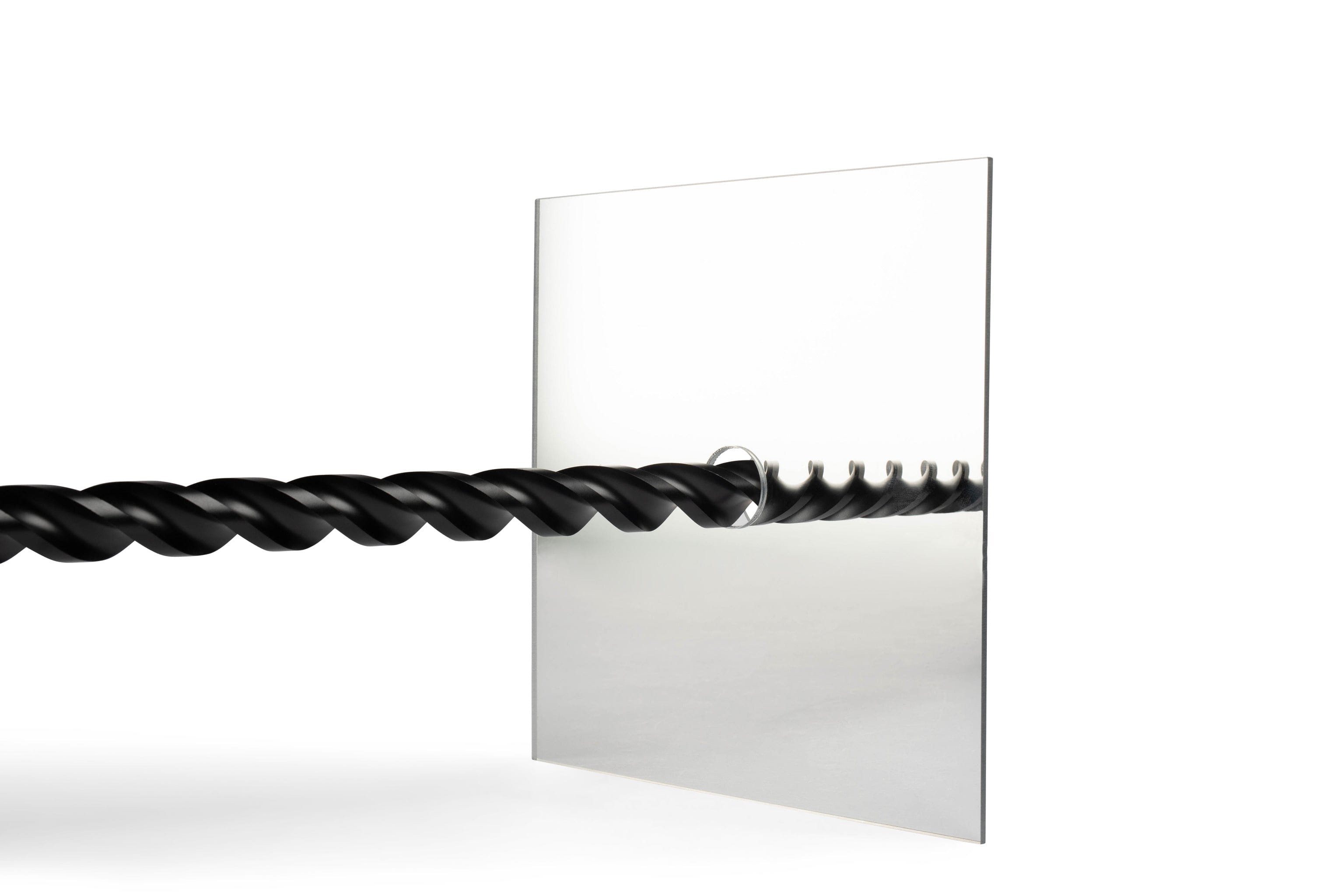 The Centering Mirror by Shelter Institute features a twisted black rod passing through a clear pane drilled at a precise 90-degree angle, creating a symmetrical mirrored effect akin to timber framing on the opposite side.