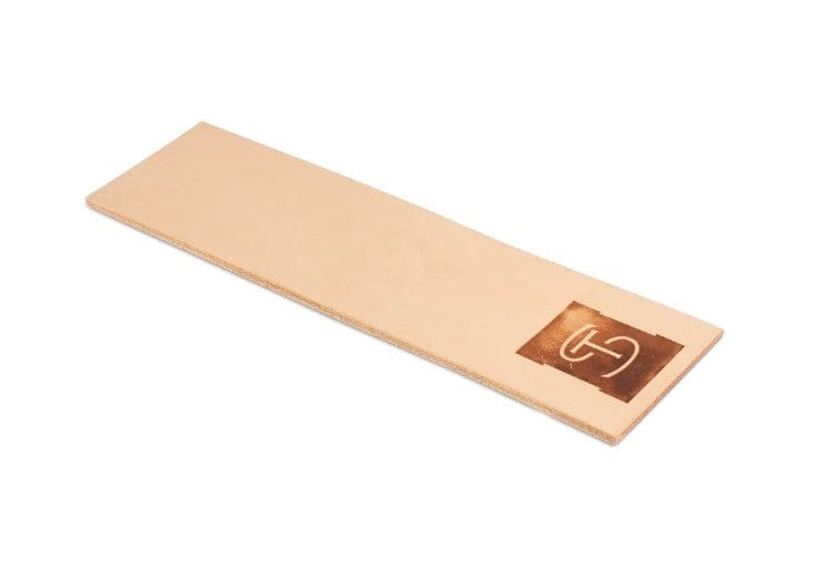 A rectangular, light tan Shelter Institute leather strop with a dark brown square and white logo—perfect for your Shelter Sharpening Kit or any woodworking sharpening kit.