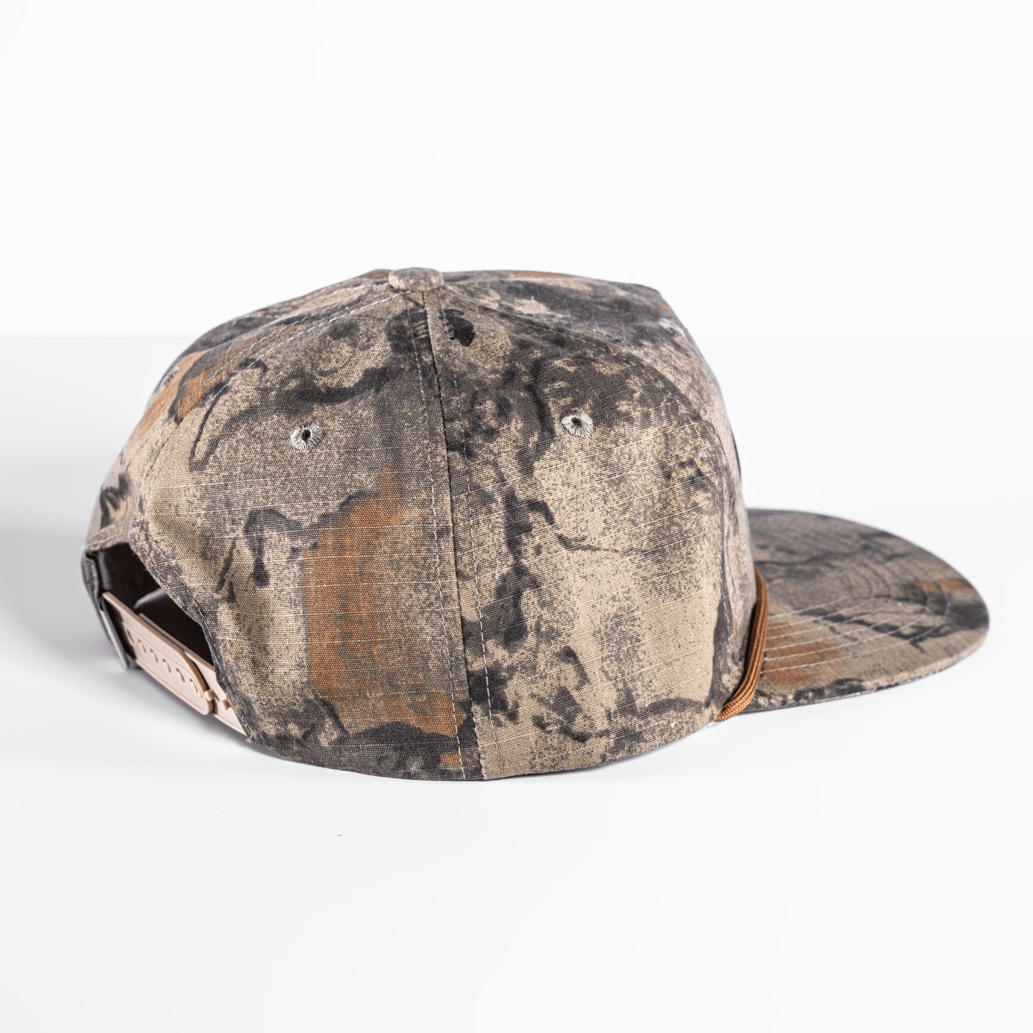 The Shelter Institute Camo Hat features a camouflage pattern, flat brim, and adjustable strap on a pristine white surface.