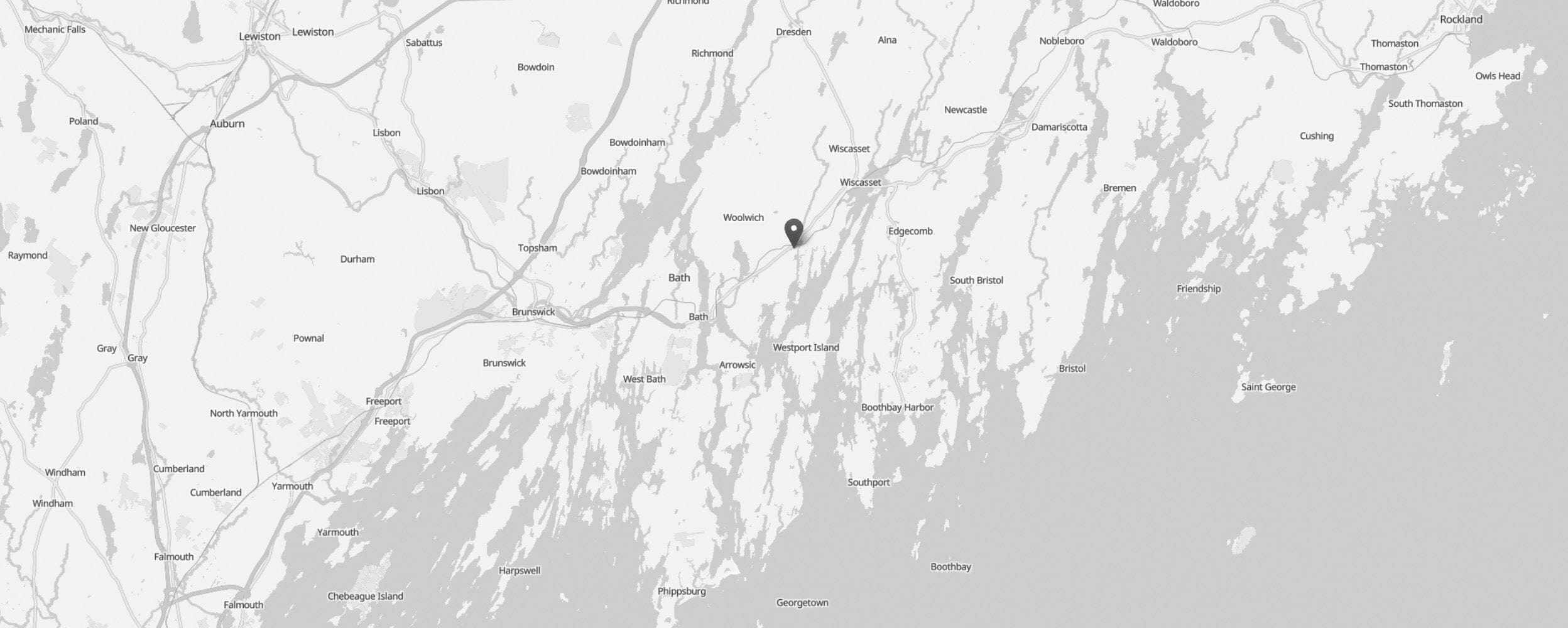 Black and white map showing coastal Maine, including towns like Brunswick, Bath, and Wiscasset. A location pin marks the area near Damariscotta—home to Shelter Institute and renowned for timber framing tools along the scenic coastline.