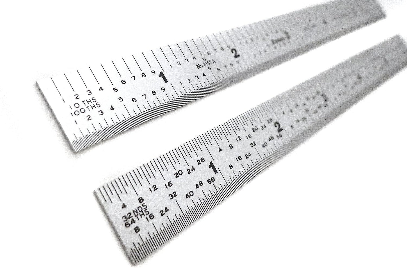 Two SHWA 6-in Rule 5R Narrow Shinwa stainless steel rulers with precise black inch markings and a zero-glare satin chrome finish are placed diagonally on a white background.