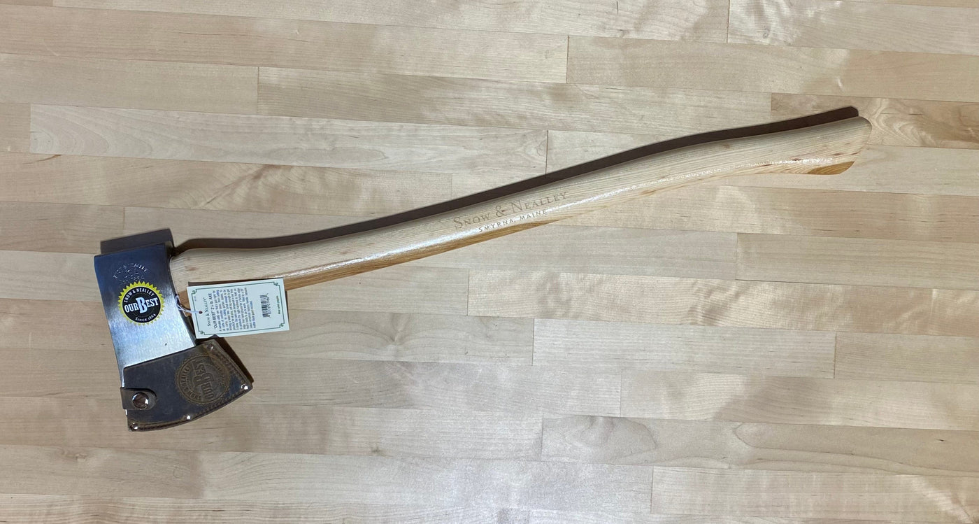 The Snow & Neally Axe 2-1/4-Lb by SNO rests on a light wooden surface, displaying its shiny high-carbon steel head and American hickory handle. A product label is attached near the head, with engraved SNO branding on the handle.