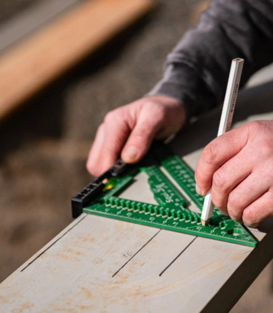 Using the Squi.Jig Fusion 7.5 inch Pro Rafter Square and a pencil, a person marks precise lines on a wooden board.