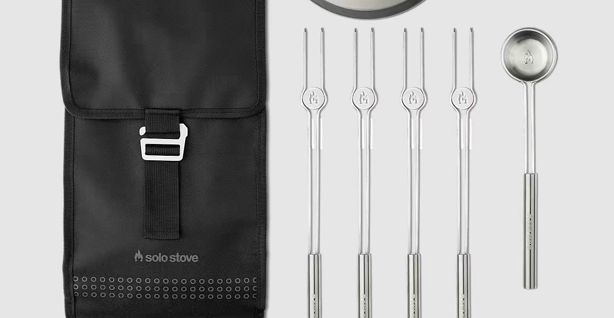 The SSO Mesa XL Accessory Pack, featuring a black carrying case, four stainless steel roasting sticks, a round silver tray, and a ladle, is arranged on a light gray background—ideal for your tabletop fire pit or Mesa XL.