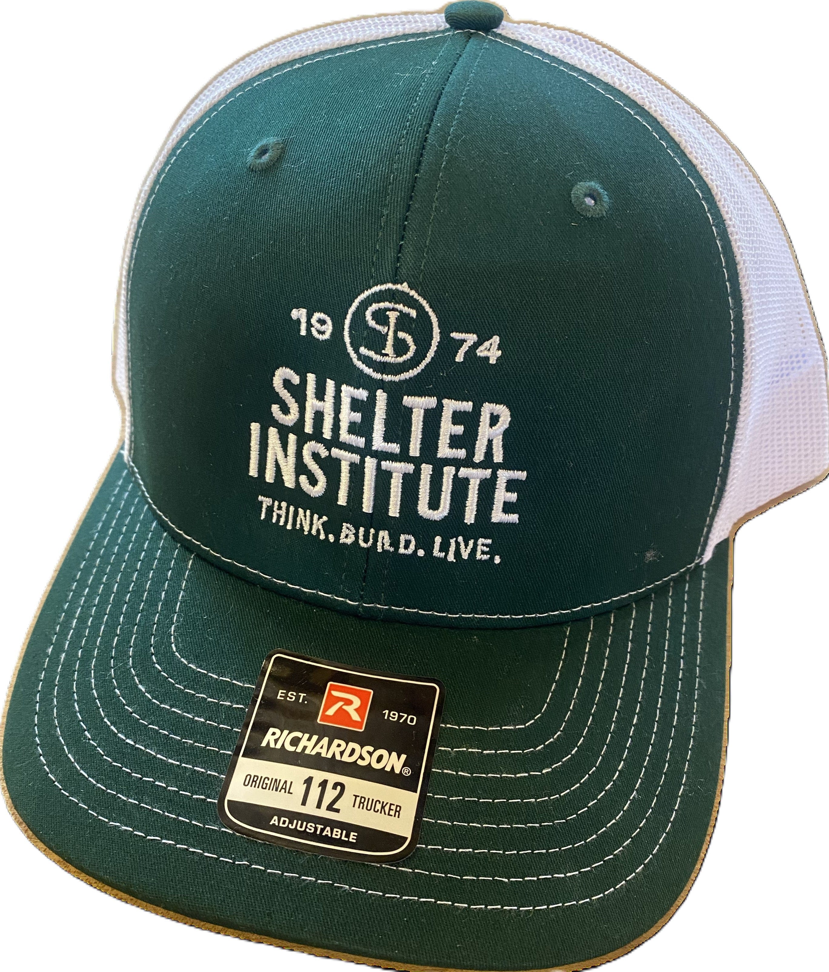 The Shelter Institute Trucker Hat by Stitch America is a green and white cap featuring SHELTER INSTITUTE 1974 THINK. BUILD. LIVE. and a Maine emblem embroidered on the front, plus a RICHARDSON Original 112 Trucker Adjustable sticker on the brim.