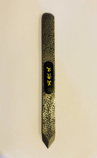 The MARU Japanese Marking Knife is a textured metal tool with a pointed end, featuring gold and black markings in the middle, ideal for woodworkers seeking precision in their craft.