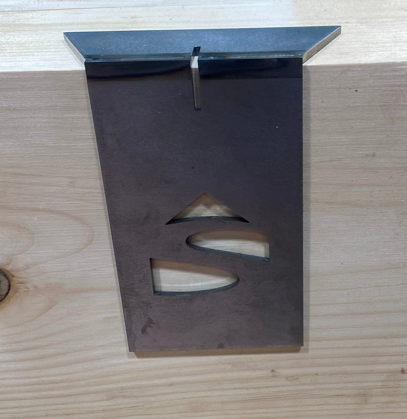 The Timber Frame Dovetail Layout Jig by Engineering Paige Trucks Restoration is a metal plaque with triangle and wave-shaped cut-outs, perfect for marking dovetail joinery on wooden surfaces in timber framing.