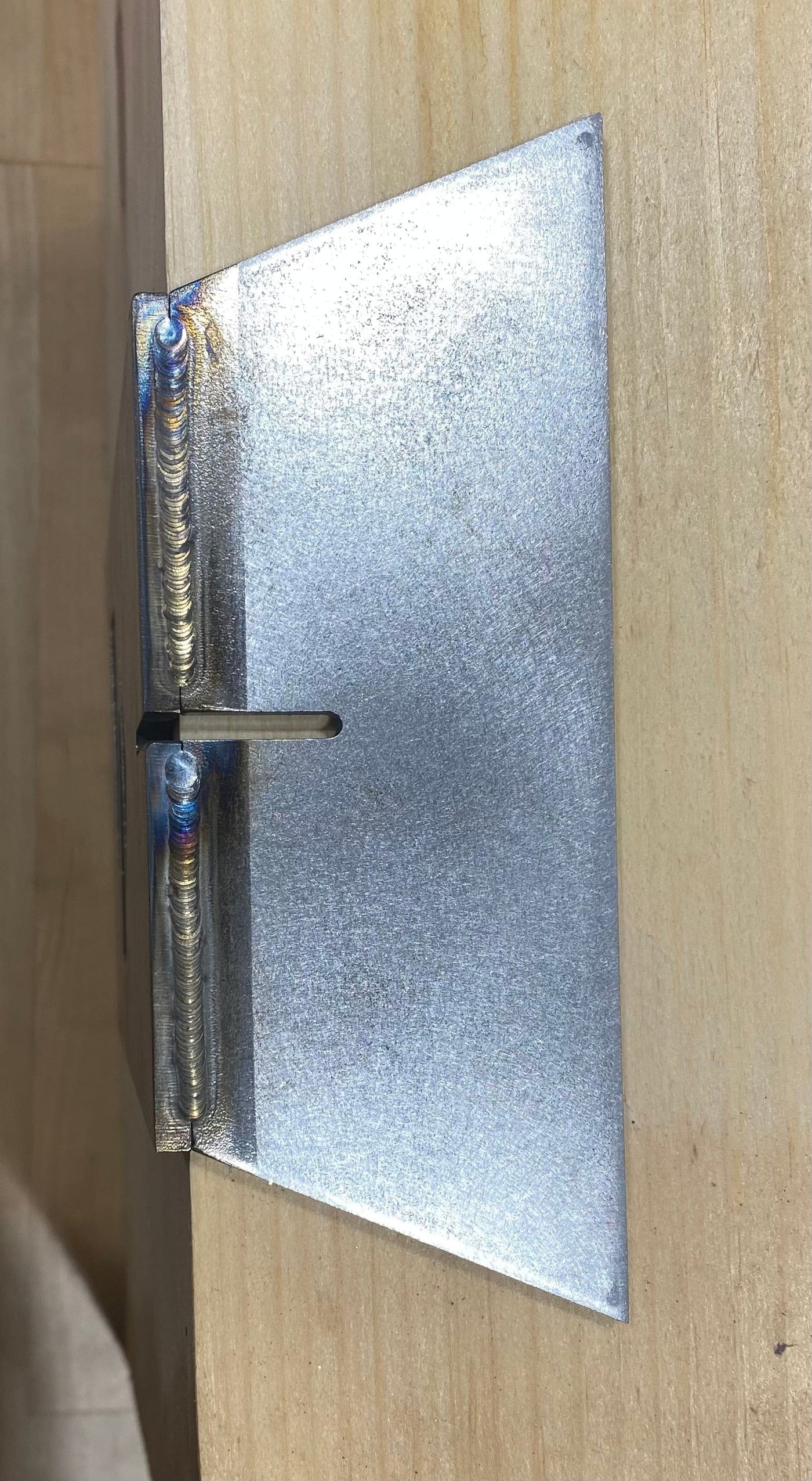 A metal bracket with precise welds and an angled design attaches to wood. Its shiny finish and slot suit dovetail joinery or use with the Engineering Paige Trucks Restoration Timber Frame Dovetail Layout Jig for timber framing.
