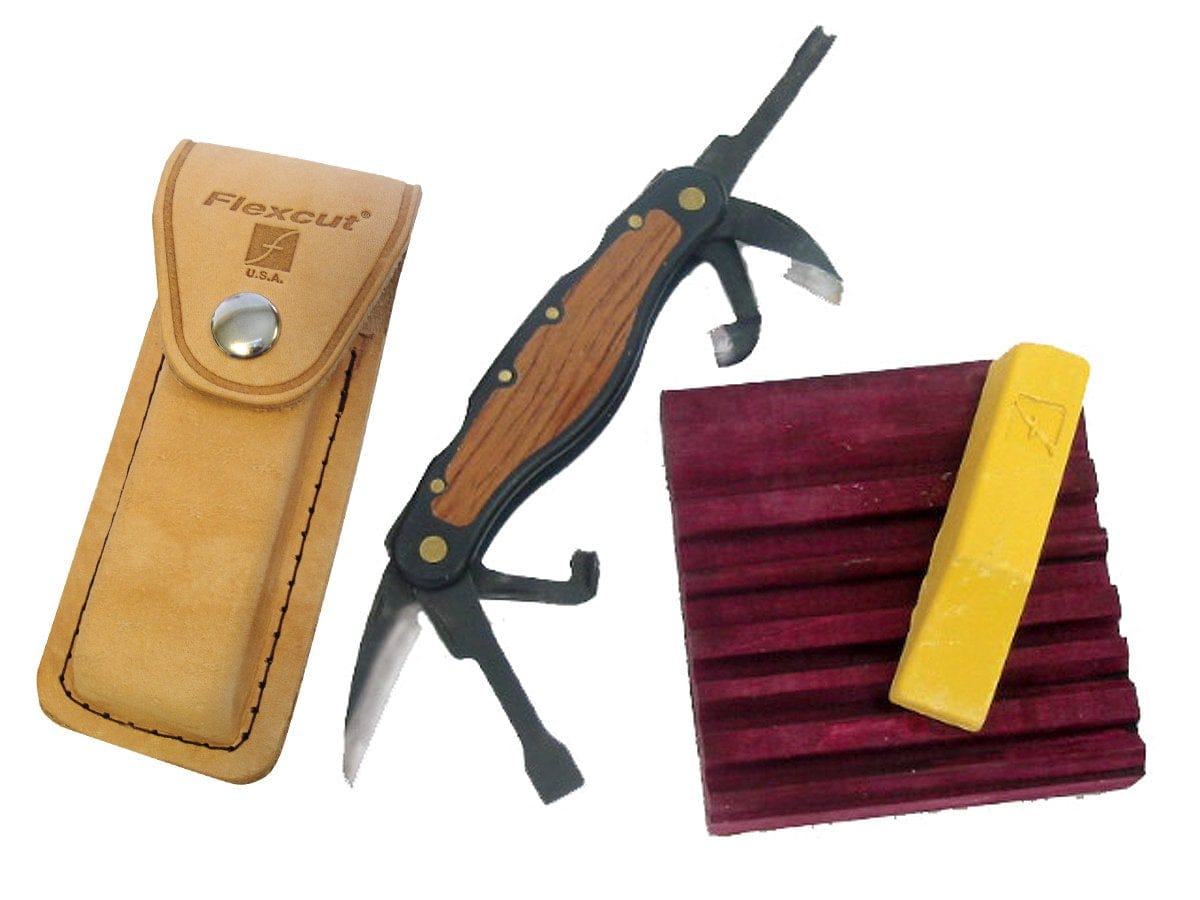 The FLE Carvin Jack woodcarving multi-tool with a wooden handle, tan leather case, grooved maroon Slipstrop sharpening block, and yellow compound bar is displayed on a white background.