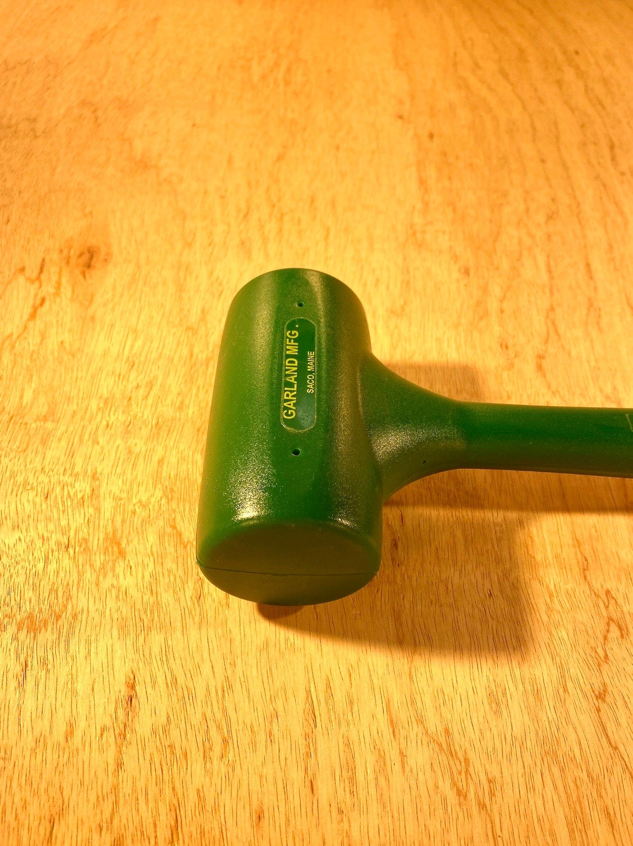 The GAM Garland Dead Blow Mallet, made of cast polyurethane, rests on a wooden surface, highlighting its durable self-healing feature.
