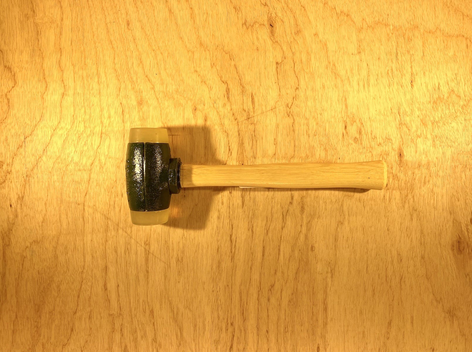 A Split Head Hammer Urethane Face with a wooden handle and dark metal head from GAM is on a wooden surface.