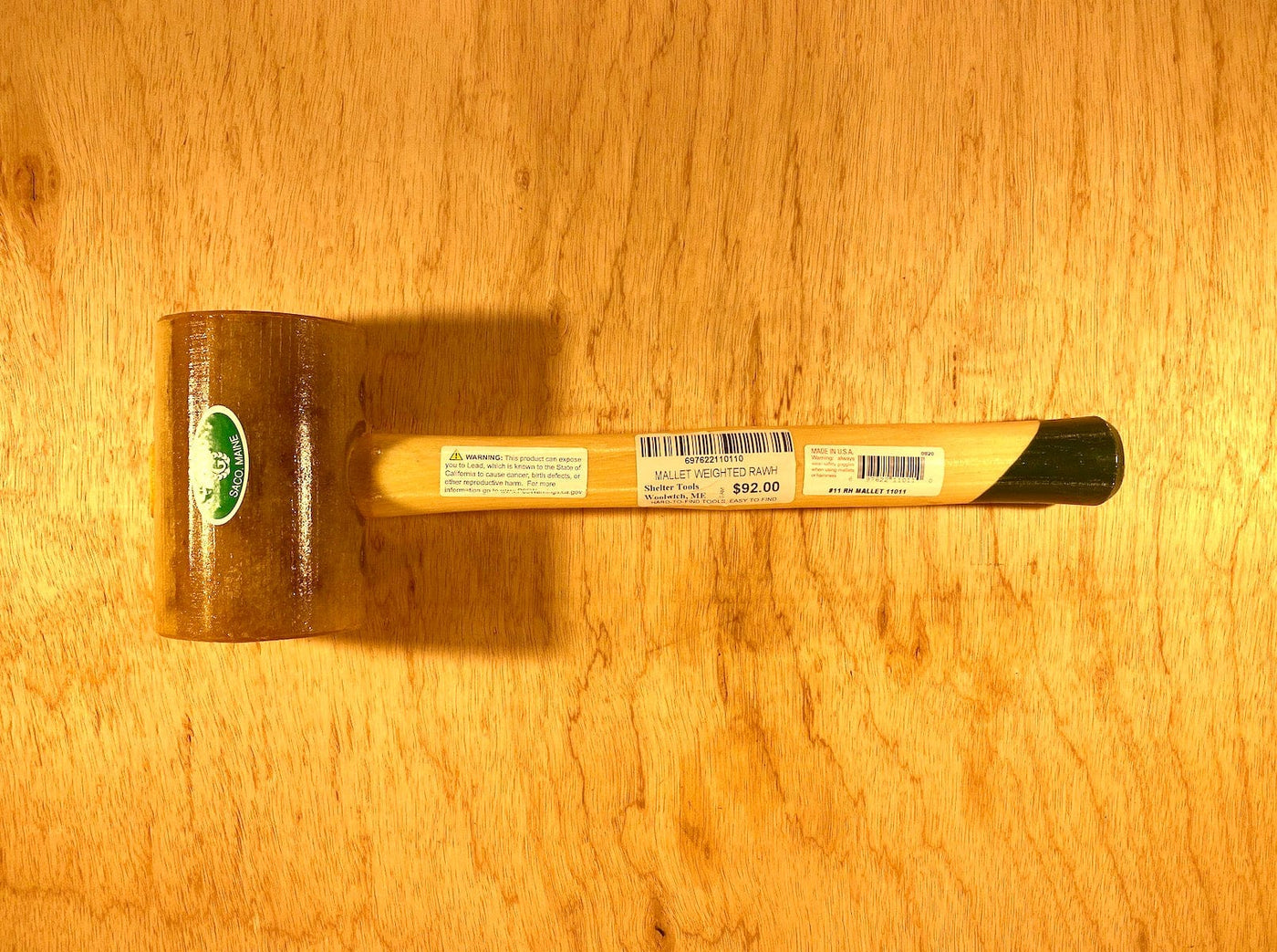 A Garland Weighted Rawhide Mallet by GAM, showcasing a green logo and priced at $22.00, rests on a wooden surface.