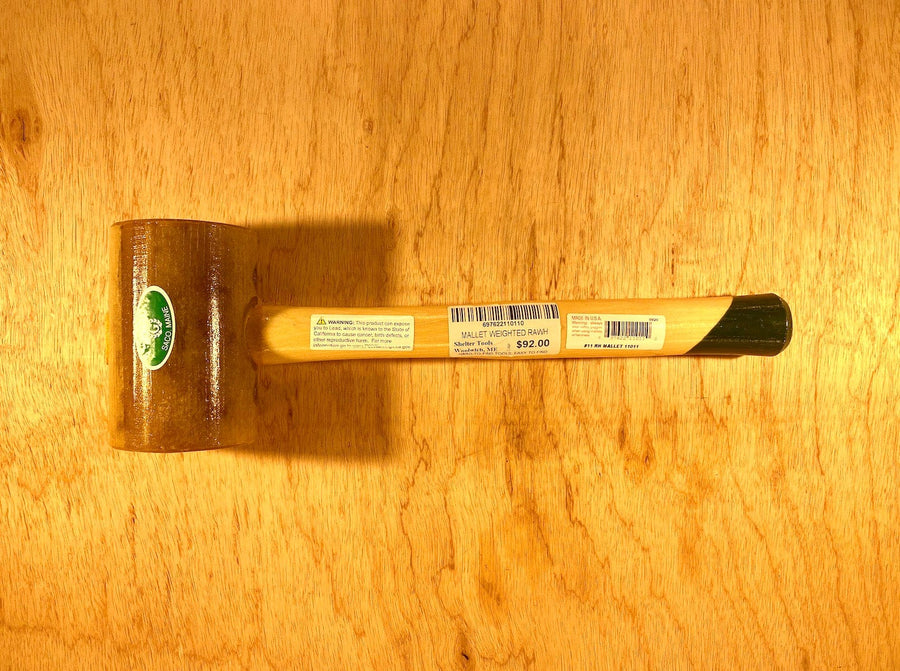 A Garland Weighted Rawhide Mallet by GAM, showcasing a green logo and priced at $22.00, rests on a wooden surface.