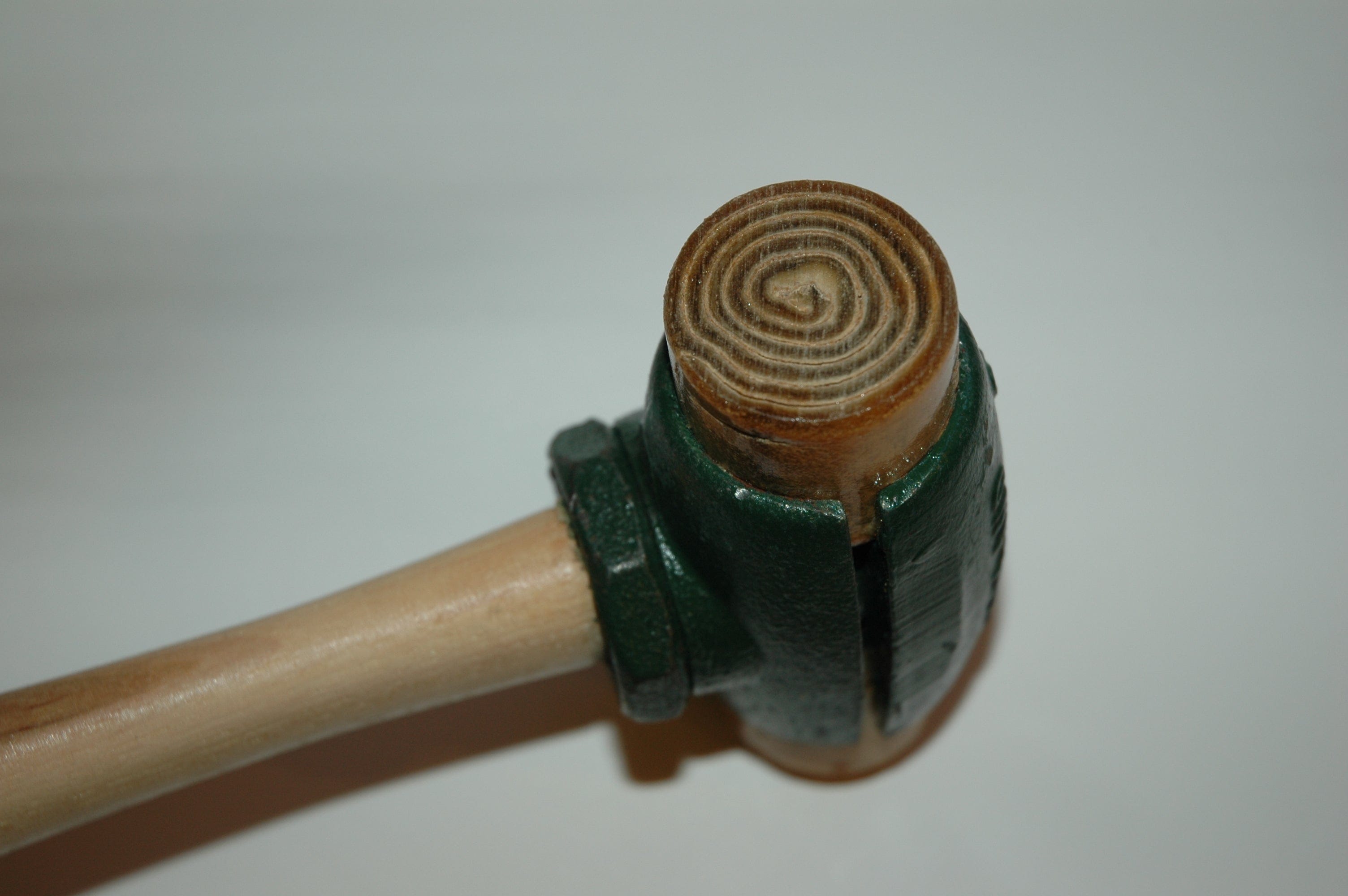 A green and wooden Split Head Hammer Rawhide Face from GAM, featuring interchangeable heads and a circular pattern on the striking surface.