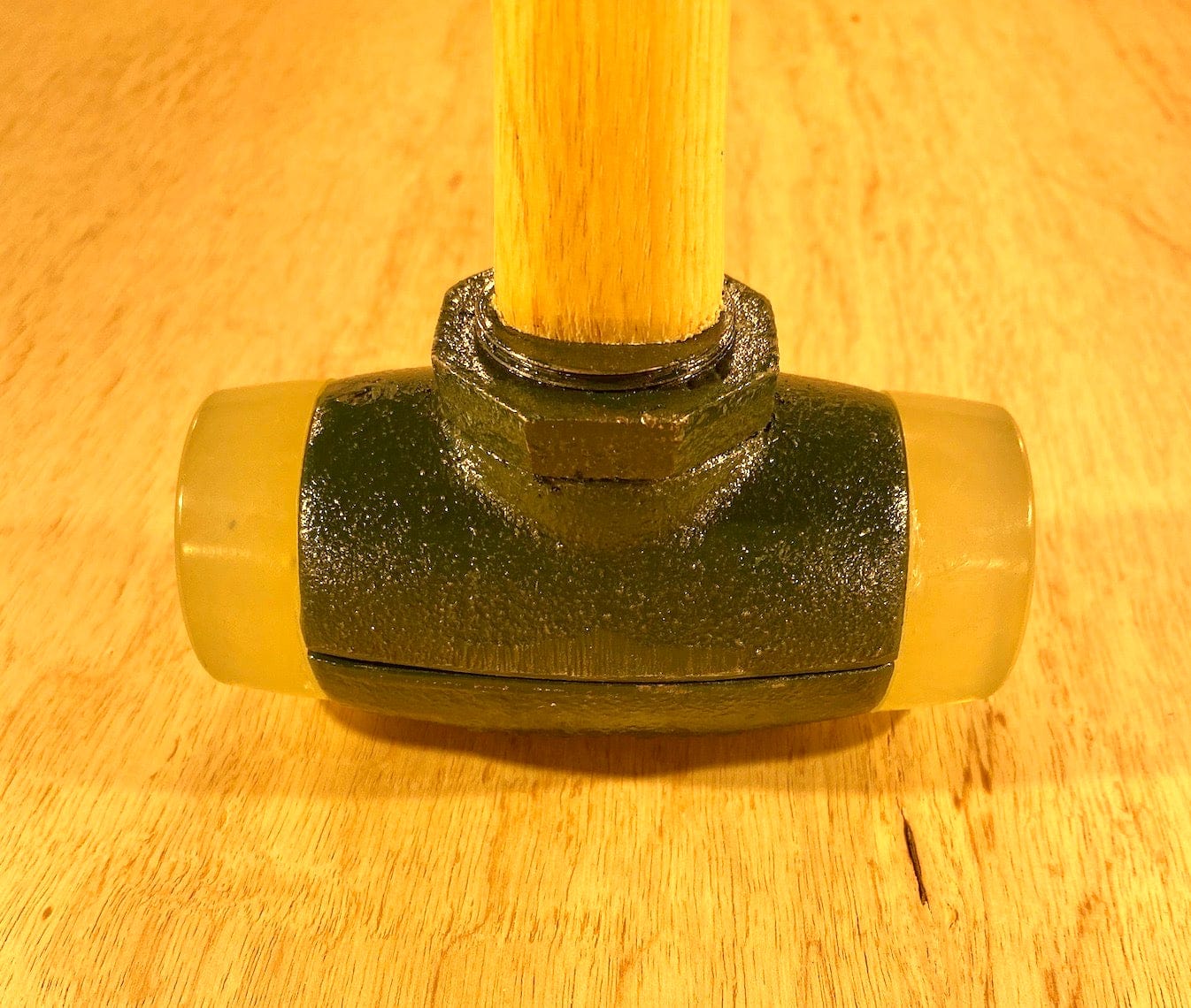 A Split Head Hammer Urethane Face with a wooden handle, crafted by GAM, rests elegantly on a wooden surface.