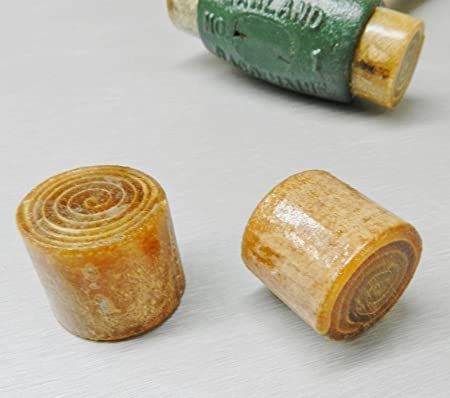Two cylindrical brown dog treats with spiral-patterned ends are shown on a light surface, with a GAM Replacement Face for Garland Mallets in green visible in the background.