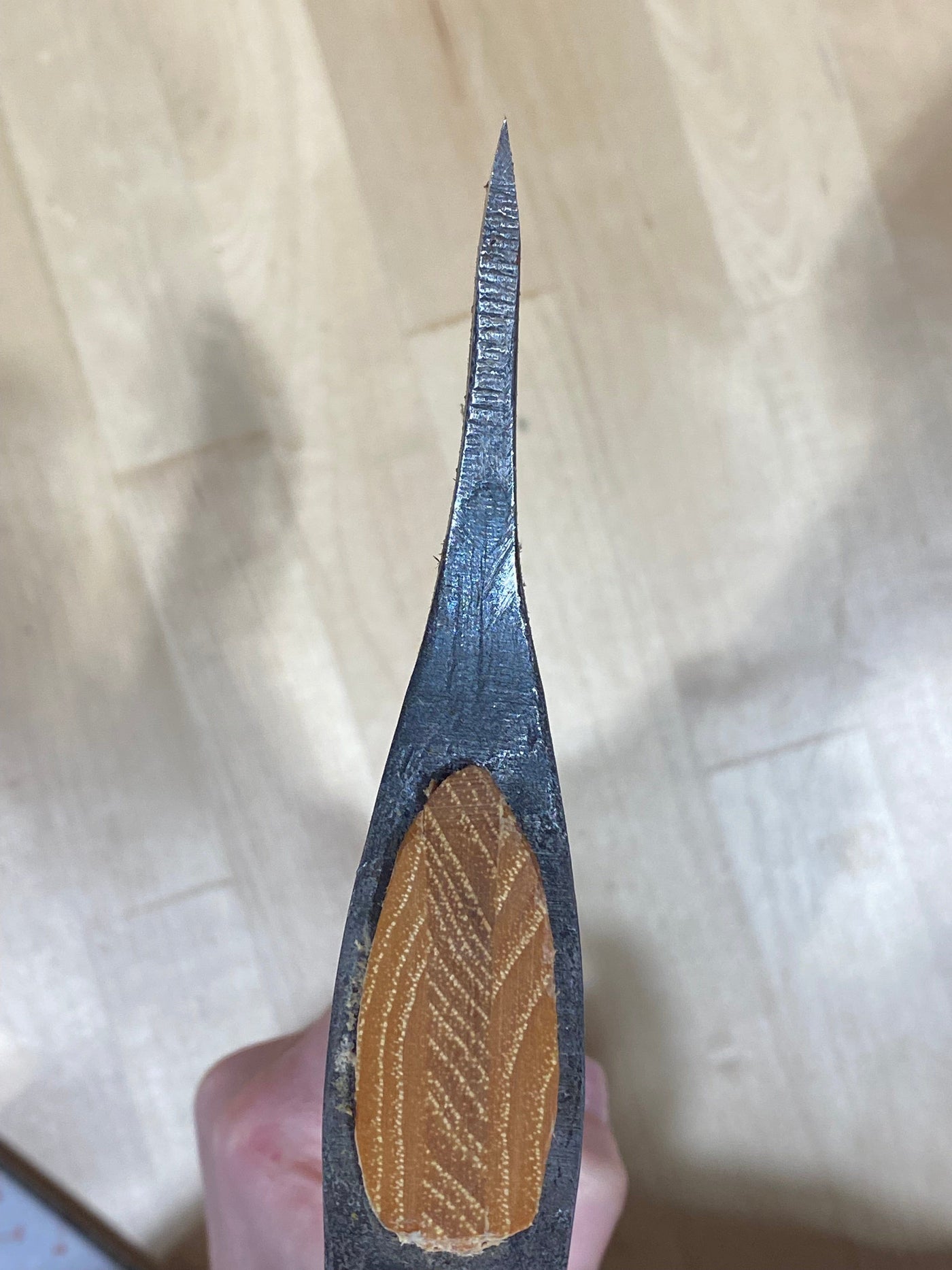 Close-up view of a Gransfors Bruk Large Swedish Carving Axe by GRF, featuring a wooden handle and sharp metal blade, photographed from above on a light wooden surface. This tool is reminiscent of traditional Swedish carving techniques.
