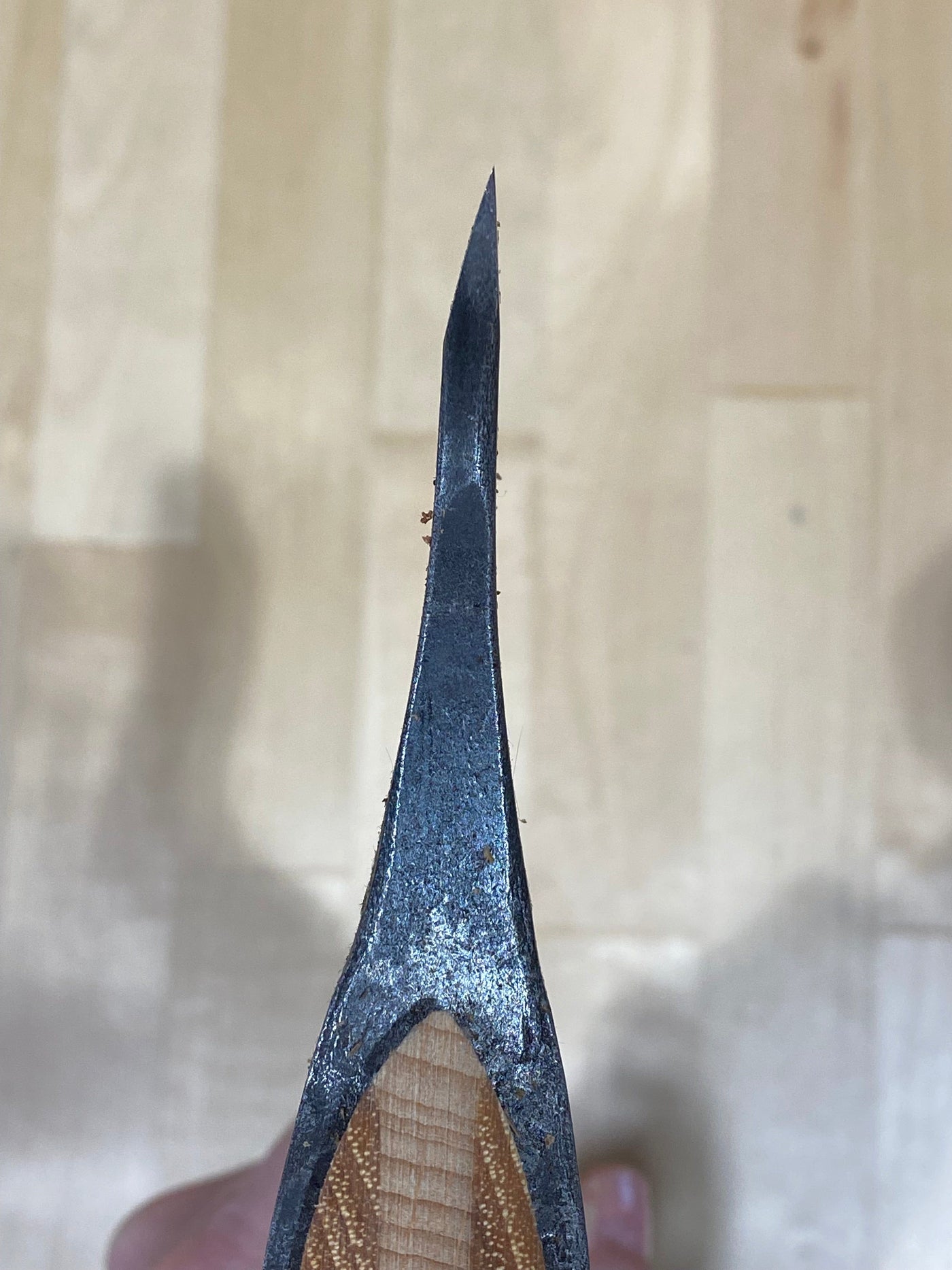 A close-up of the GRF Gransfors Bruk Large Swedish Carving Axe showcases its sharp curved edge and wooden handle, set against a wooden floor backdrop, reflecting traditional Swedish carving techniques.