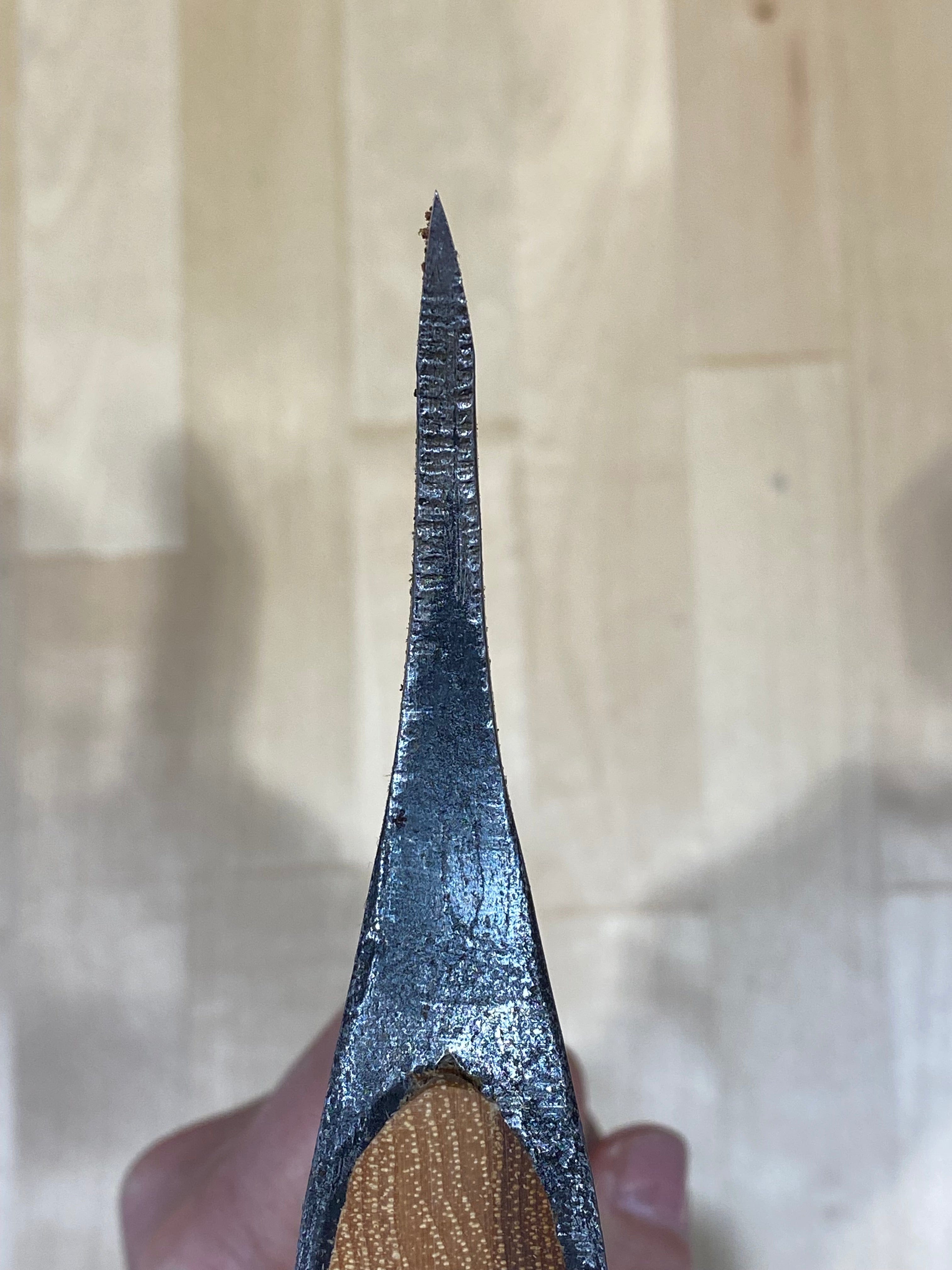 Close-up of a Gransfors Bruk Large Swedish Carving Axe by GRF, with a sharp edge held over wood, reminiscent of traditional Swedish carving techniques.