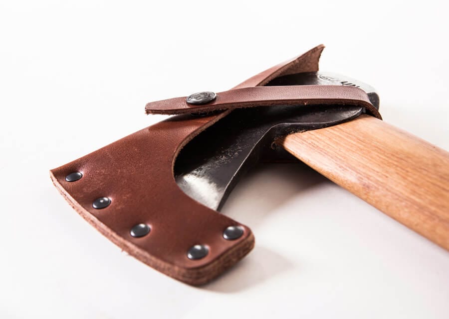 A close-up of the GRF Gransfors Bruk Hunters Axe 418 with a wooden handle and brown leather sheath featuring black rivets and snap closure, set against a white background—perfect for chopping wood.
