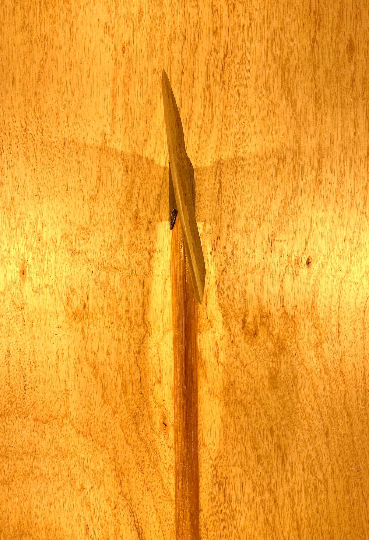 A Gransfors Bruk Broad Axe with a robust wooden handle is vertically mounted on a light timber wall, reminiscent of traditional log house building.