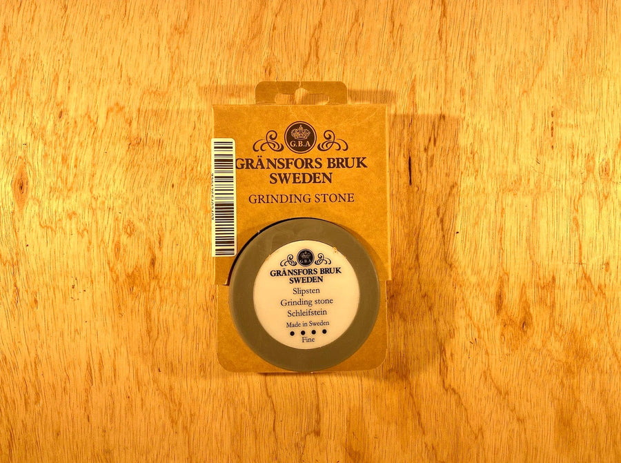 The Gransfors Bruk Ceramic Sharpening Stone by GRF is a precision tool packaged in a cardboard box labeled "Gränsfors Bruk Sweden Grinding Stone," resting on a wooden surface.